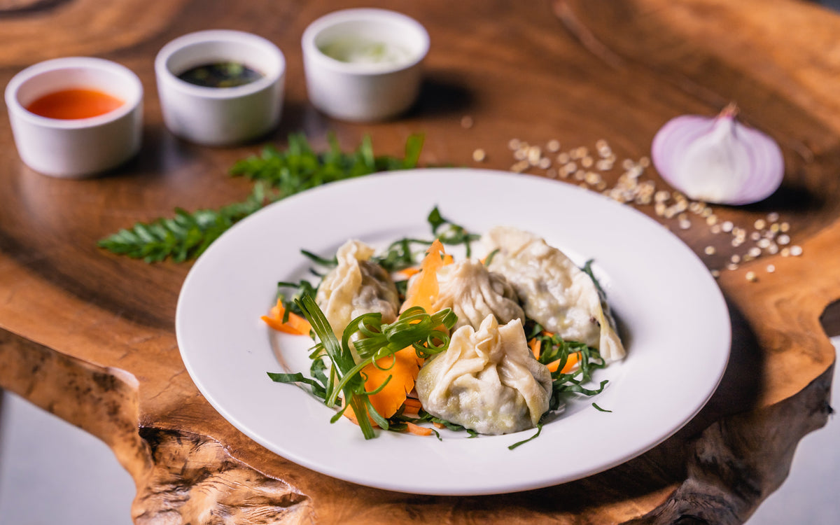 Mamtu dumplings with vegetable garnish and dipping sauces at The Shire