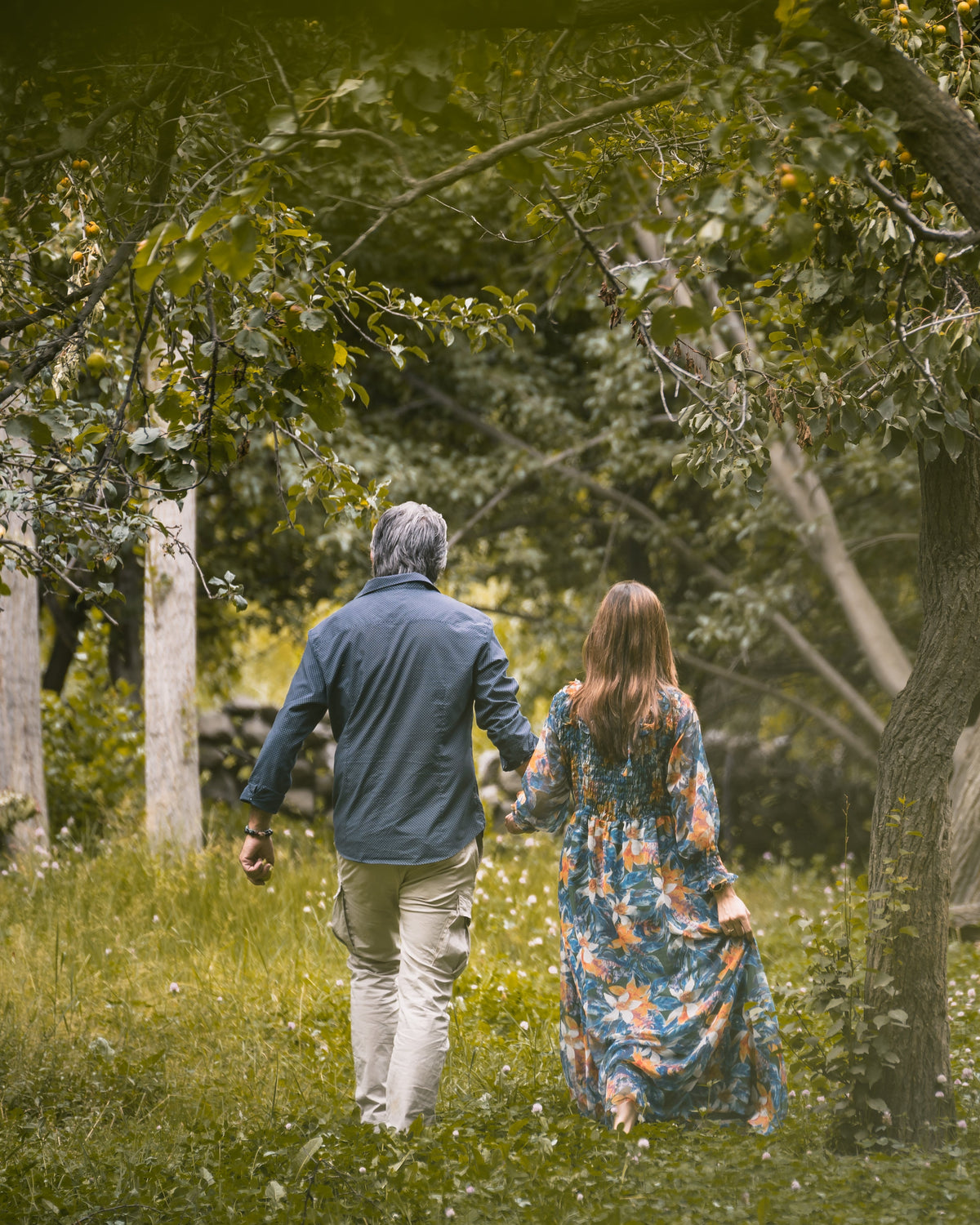 Two people walking hand in hand through the orchards at Offto Resort Karimabad